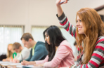 Undergraduate student with their hand up in a lecture