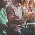 Audience members at an event clapping their hands