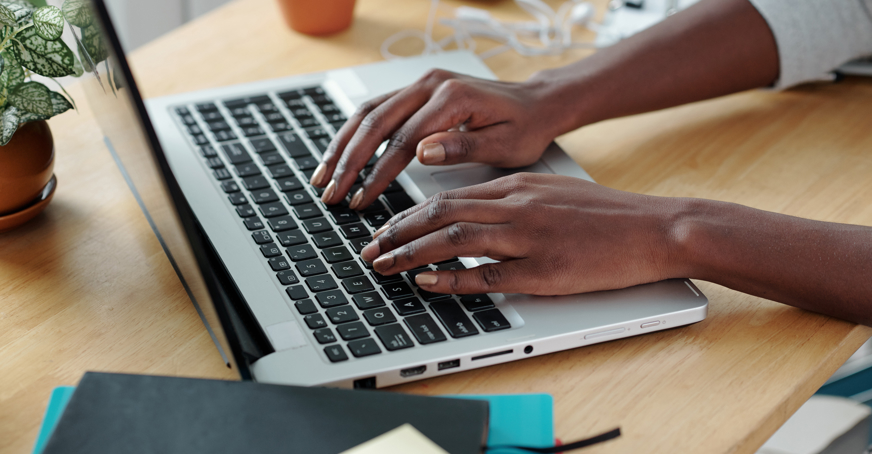 A person's hands typing on a laptop keyboard.