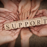 Group of hands holding wooden blocks spelling out support